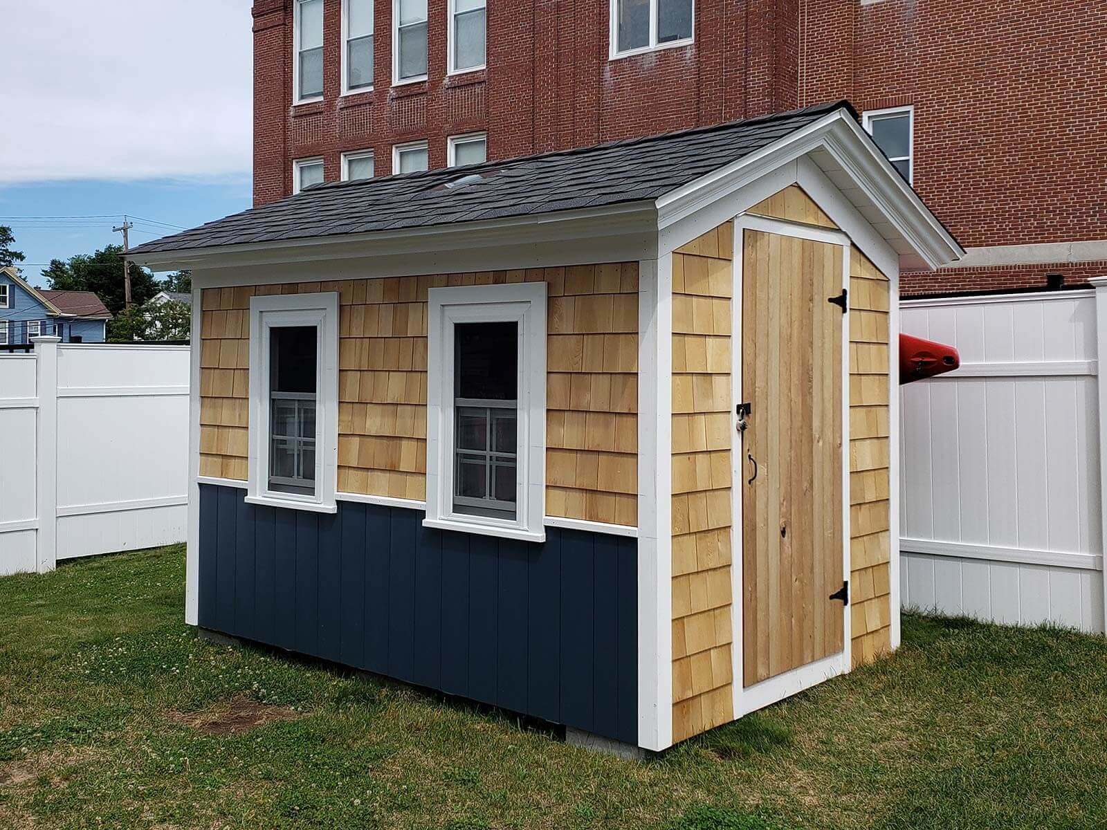 Side of black and cedar two-toned shed with two windows and white trim.