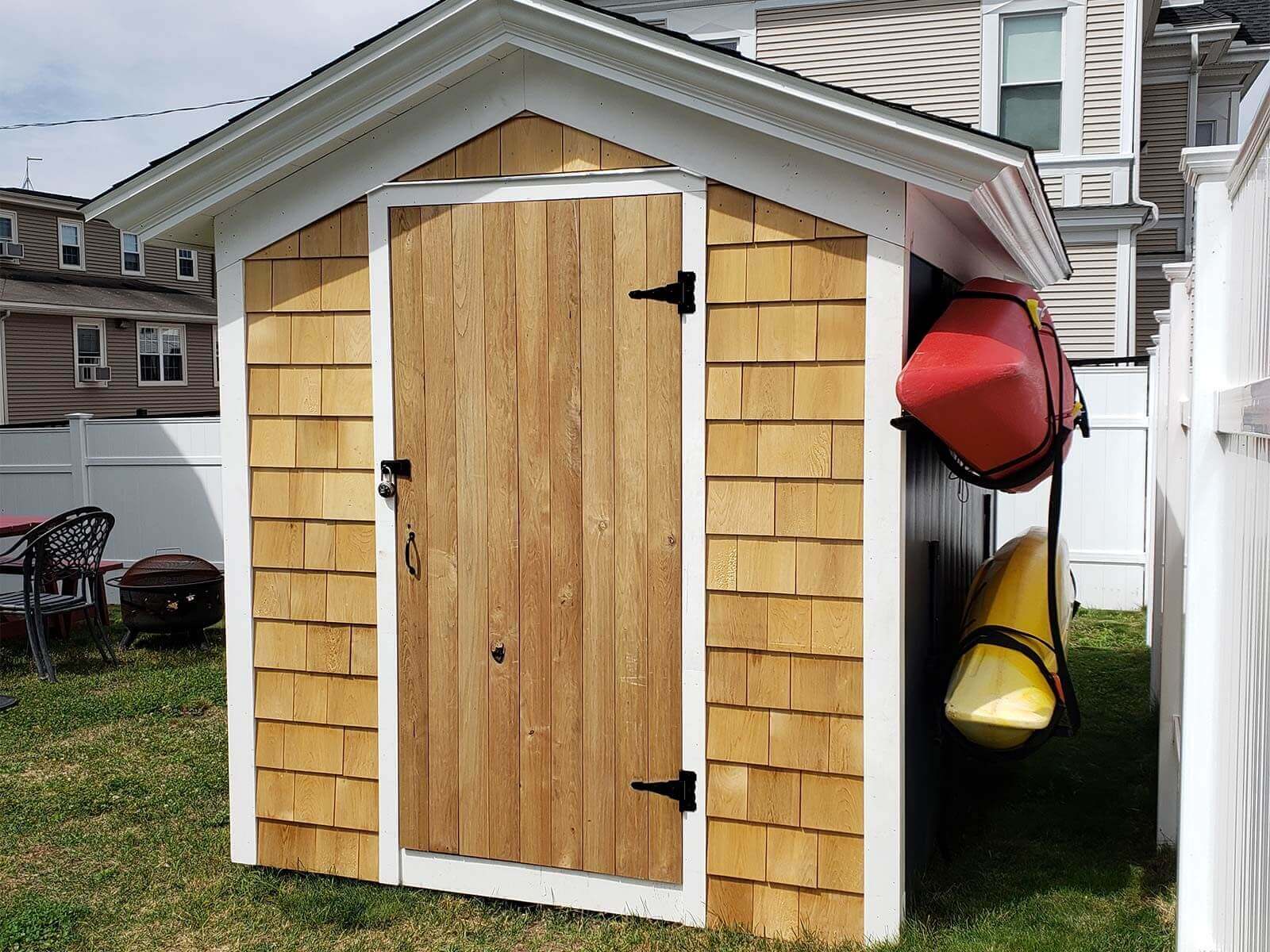 Front of cedar shed with sturdy roof and kayaks hung on one side.