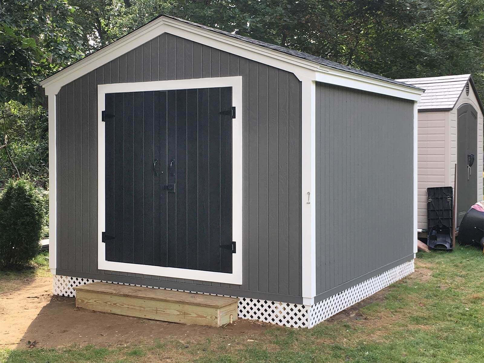 Large, raised painted shed with double doors and a wooden step.