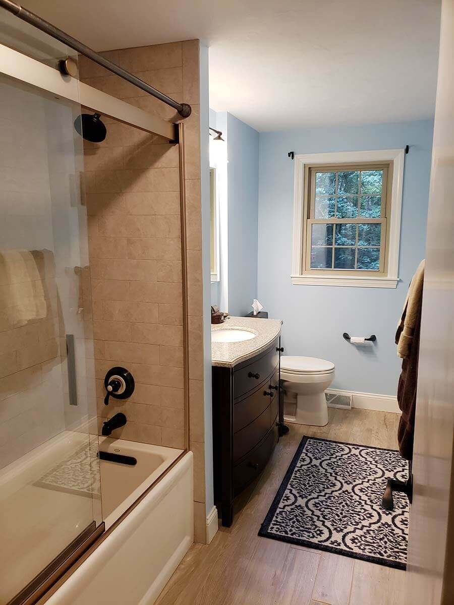 Long view of bath remodel showing tiled shower/bath with glass sliding doors.